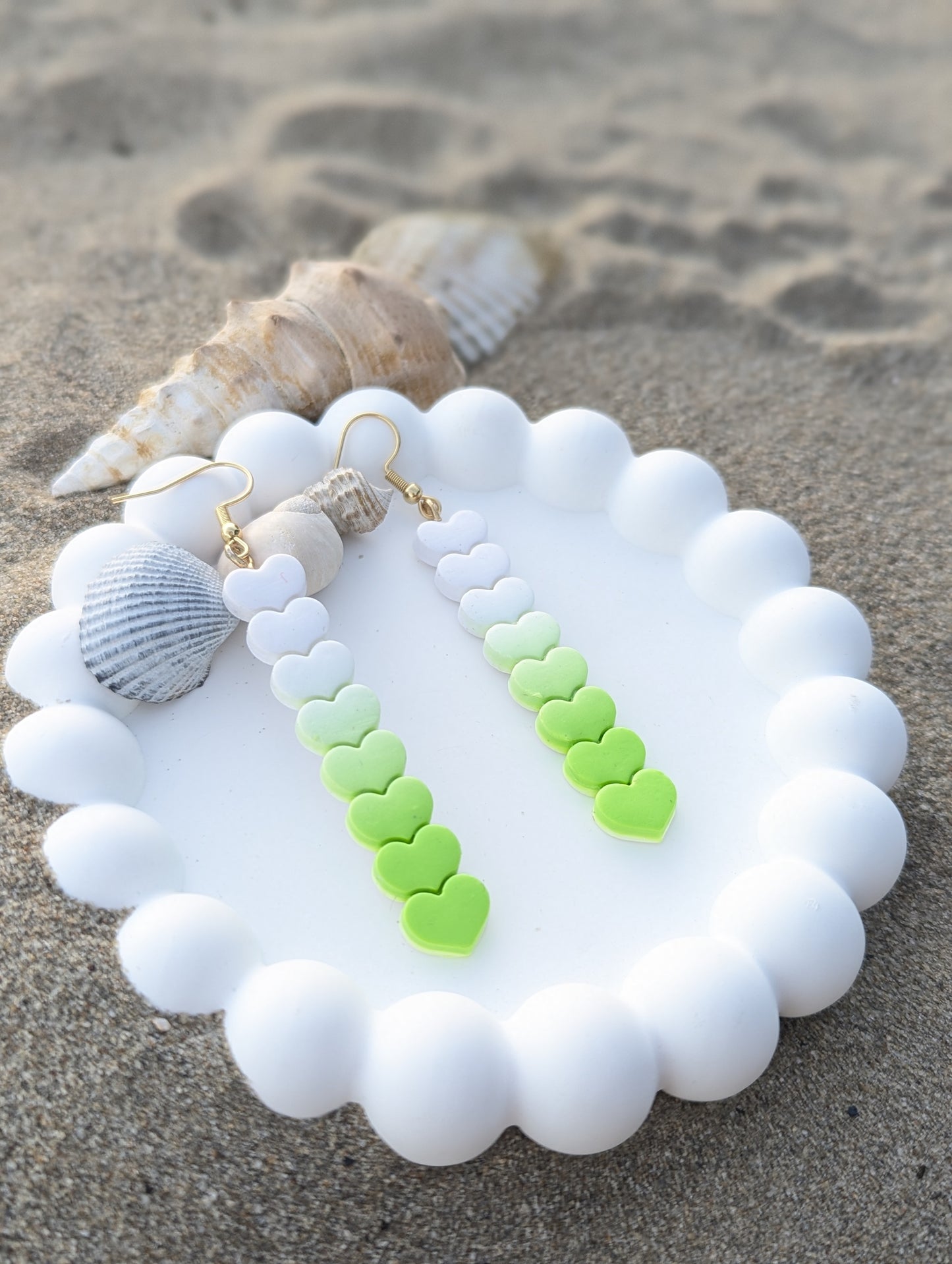 Handmade polymer clay earrings with heart shapes in a Linear white to lime green ombre gradient.