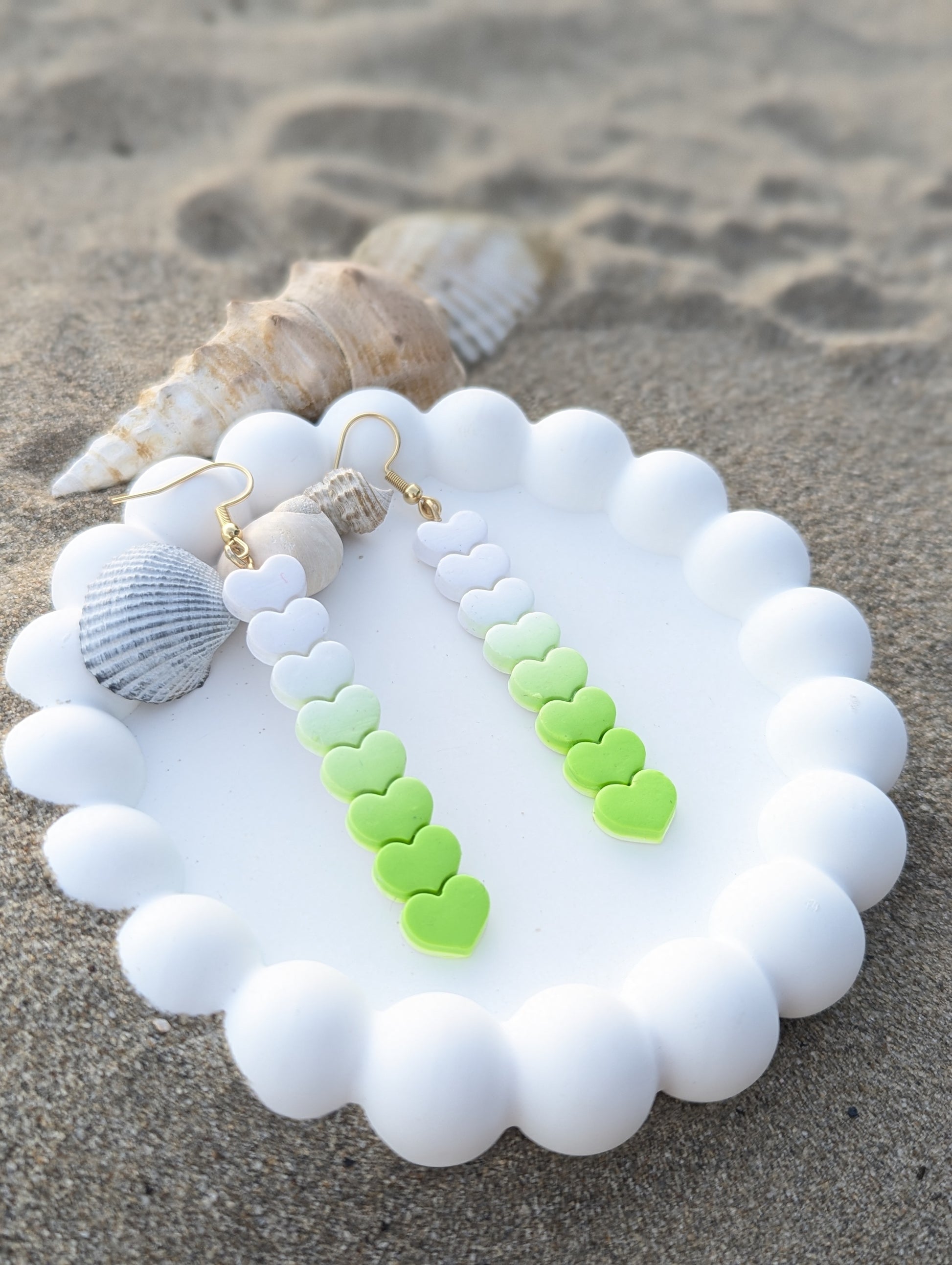 Handmade polymer clay earrings with heart shapes in a Linear white to lime green ombre gradient.