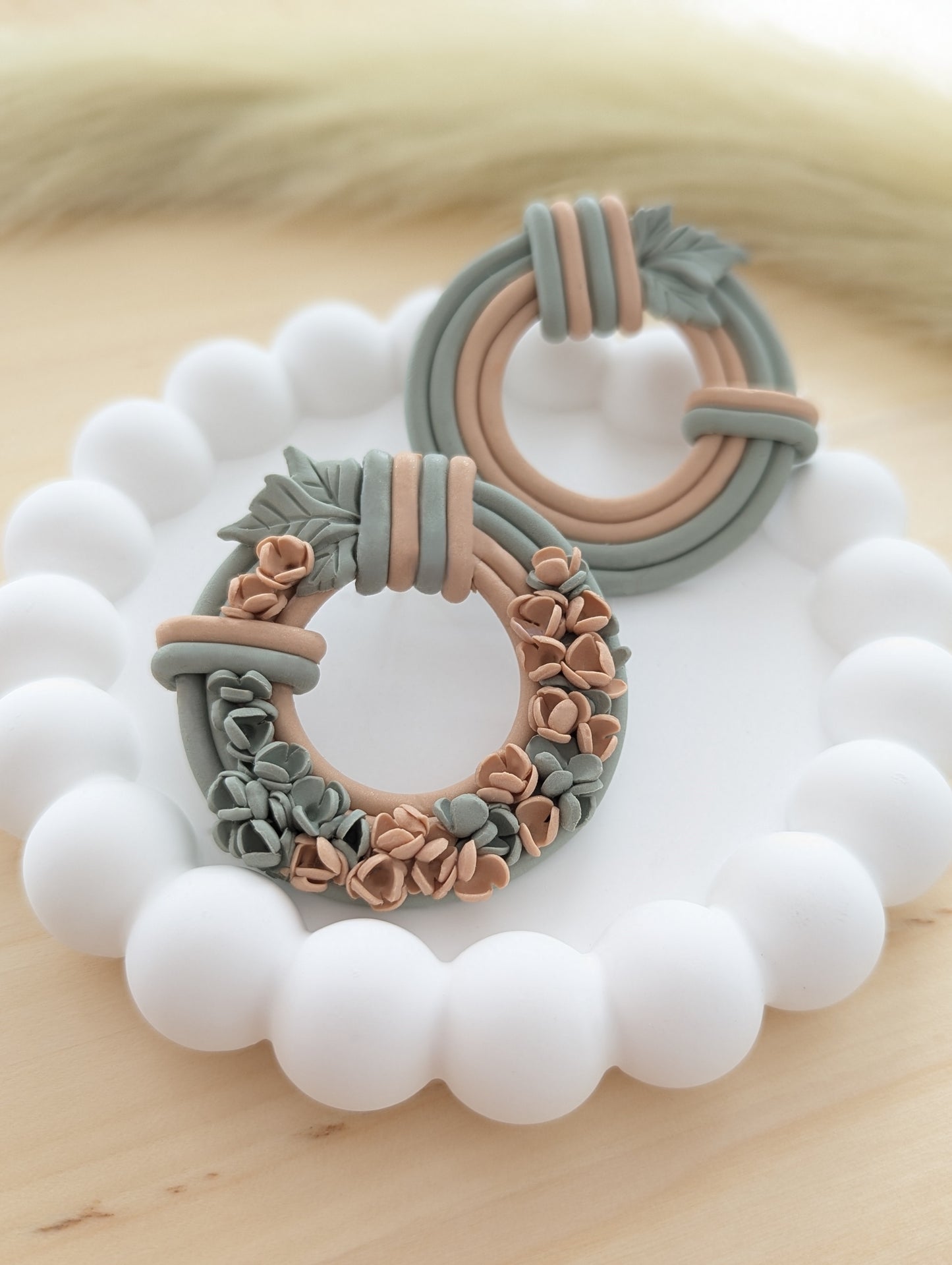 Close-up of floral wreath earrings showcasing intricate flower and leaf details by focusing on floral pair.