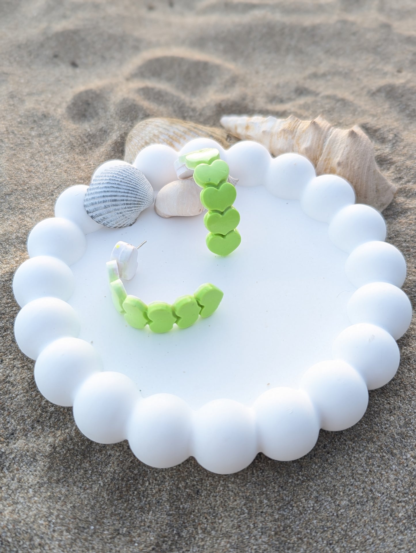 Handmade polymer clay earrings with heart shapes in a white to lime green ombre gradient. Curved Heartline display 1