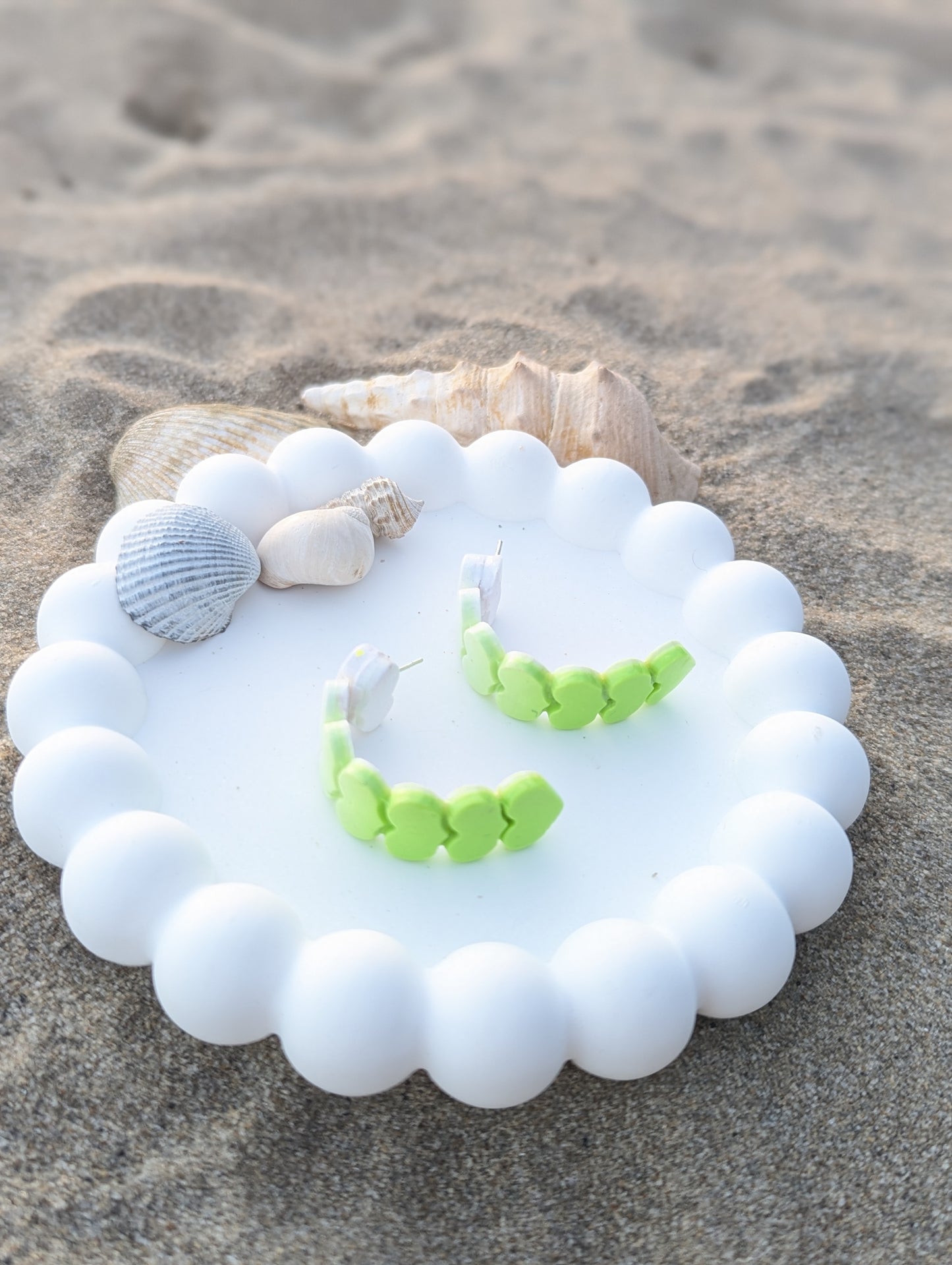 Handmade polymer clay earrings with heart shapes in a white to lime green ombre gradient. Curved Heartline display 2