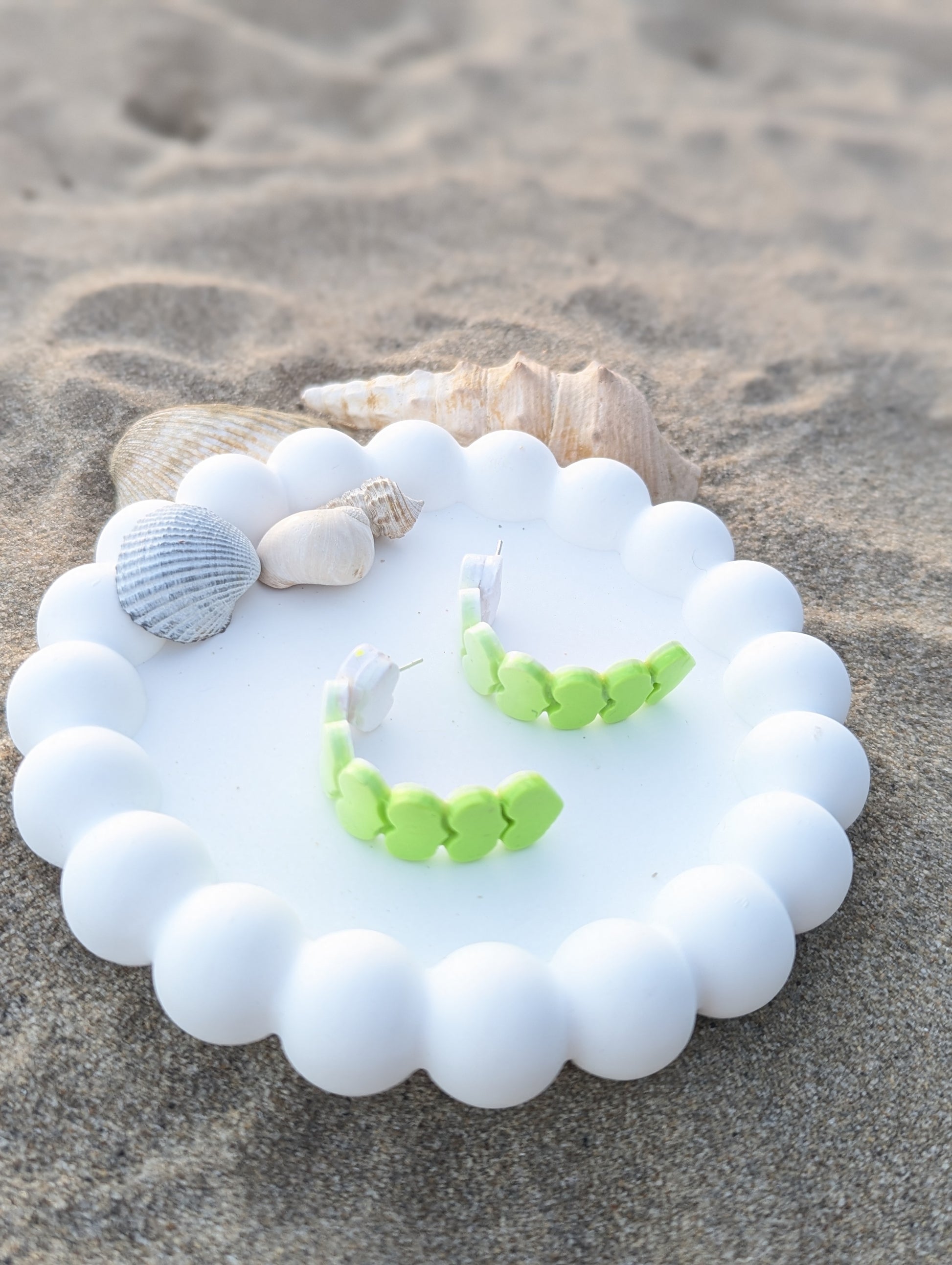 Handmade polymer clay earrings with heart shapes in a white to lime green ombre gradient. Curved Heartline display 2