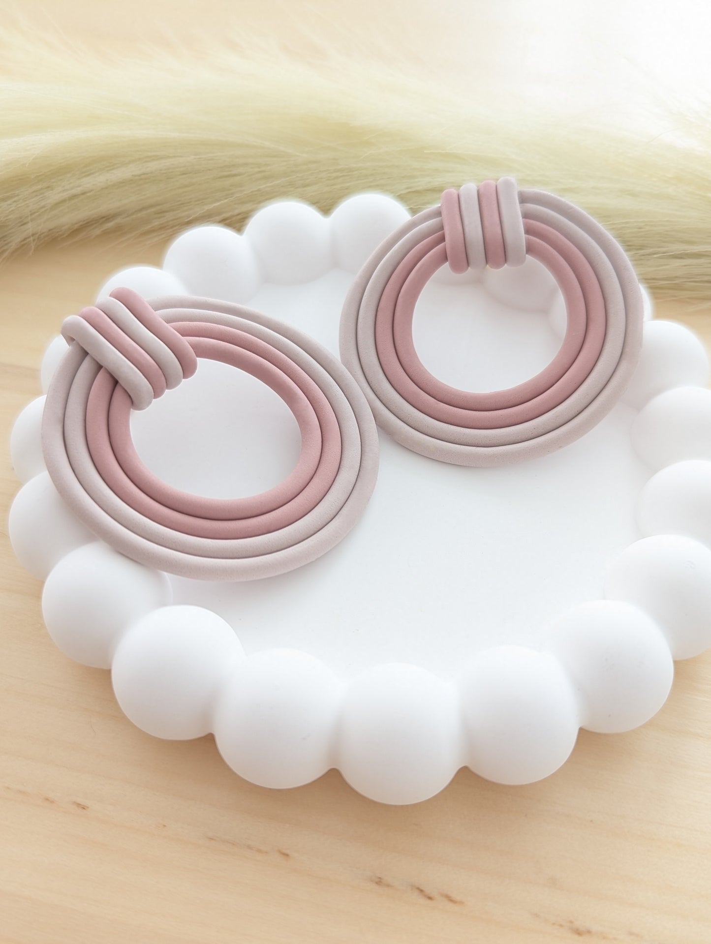 Handmade polymer clay earrings in soft pink and neutral tones, displayed on a white scalloped tray for a minimal and elegant look.
